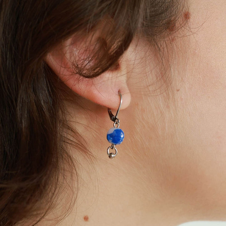 Femme portant une Boucle d'oreilles argentée avec bille bleue suspendue par ANne-Marie Chagnon