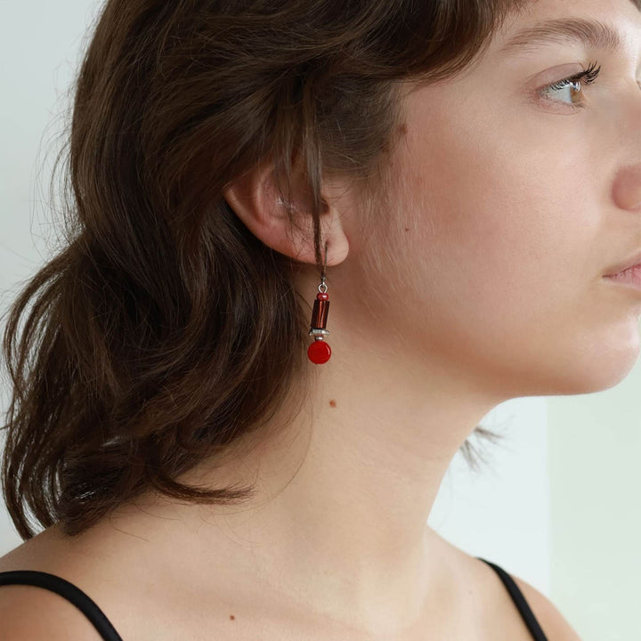 Femme portant une Boucle d'oreilles rouges suspendues par Anne-Marie Chagnon