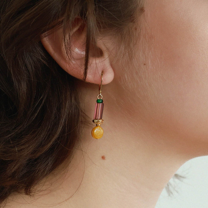 Femme portant une Boucle d'oreilles rose et orange suspendue par Anne-Marie Chagnon