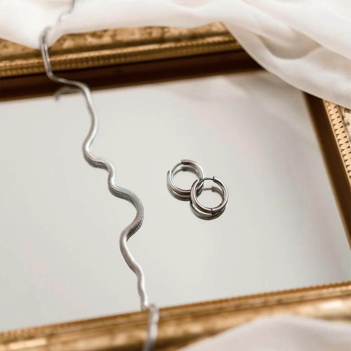 Anneaux argentés par welldunn avec collier argenté sur un miroir