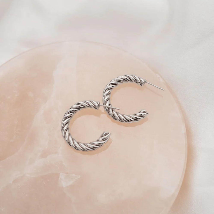 Boucles d'oreilles torsadées argentées par welldunn une sur l'autre