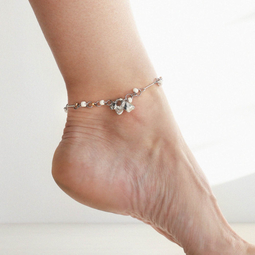 Pied avec un Bracelet argenté et doré Auriga par Anne-Marie Chagnon