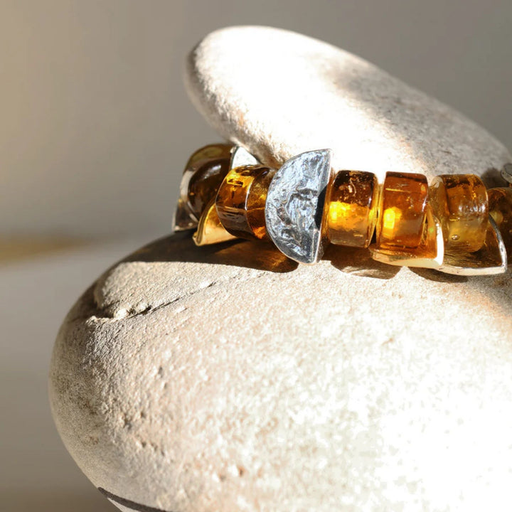 Bracelet Mankar avec pièces en verre brunes et morceaux d'étain sur une roche par ANne-Marie Chagnon