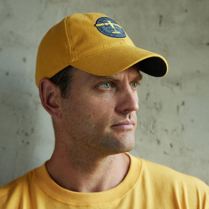 Homme portant une Casquette jaune De Havilland avec logo par Red Canoe
