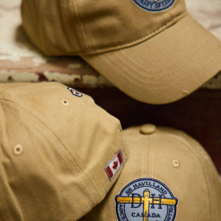 Casquettes tan De Havilland avec logo par Red Canoe empilées les unes sur les autres