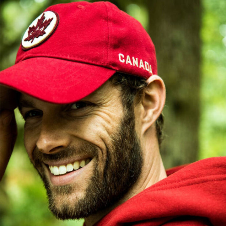 Homme dans la forêt portant une Casquette Canada rouge avec logo par Red Canoe