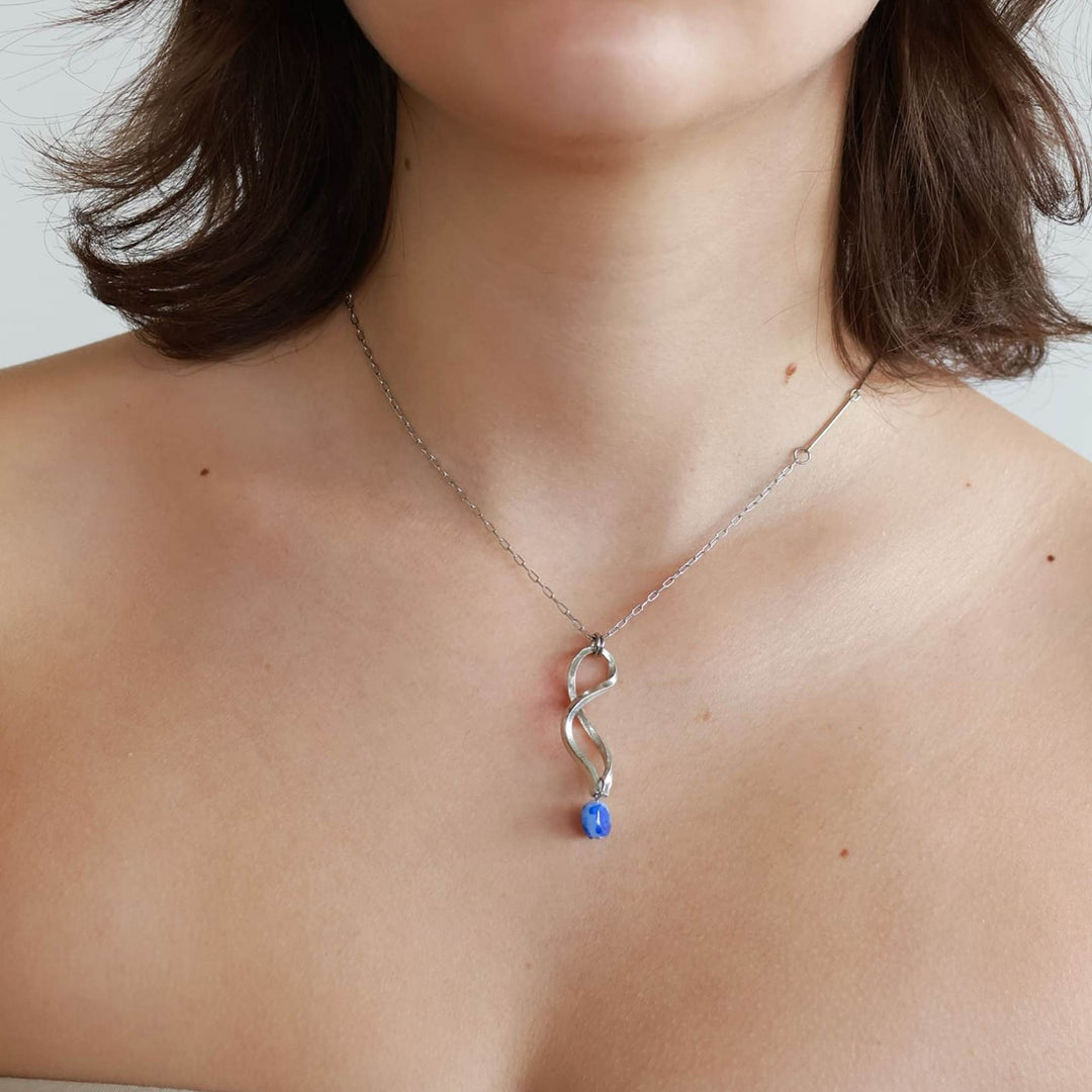 Femme portant le Collier argenté avec pendentif en spirale et pierre bleue suspendue par Anne-Marie Chagnon