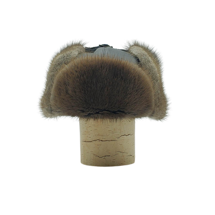 Chapeau en fourrure de rat musqué et cuir avec oreilles par Fourrures audet vu de devant sur une bûche