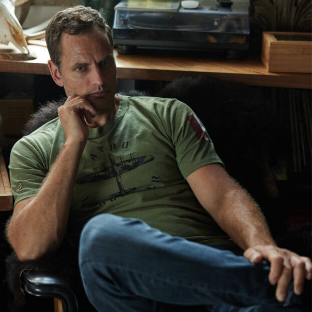 Homme assit portant un Tshirt vert kaki Avro avec un imprimé d'avion par Red Canoe