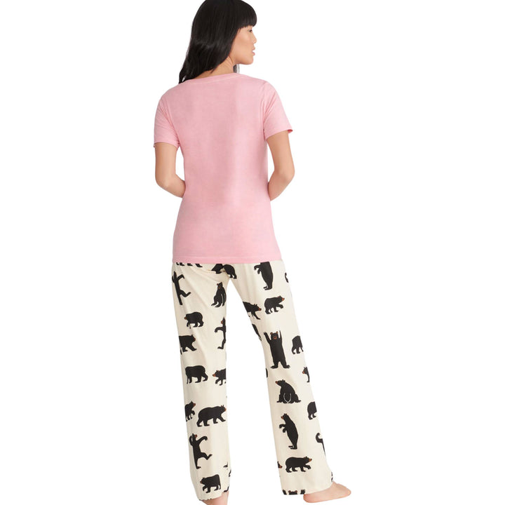Femme de dos portant un ensemble de pyjama rose et blanc avec motifs d'ours noirs