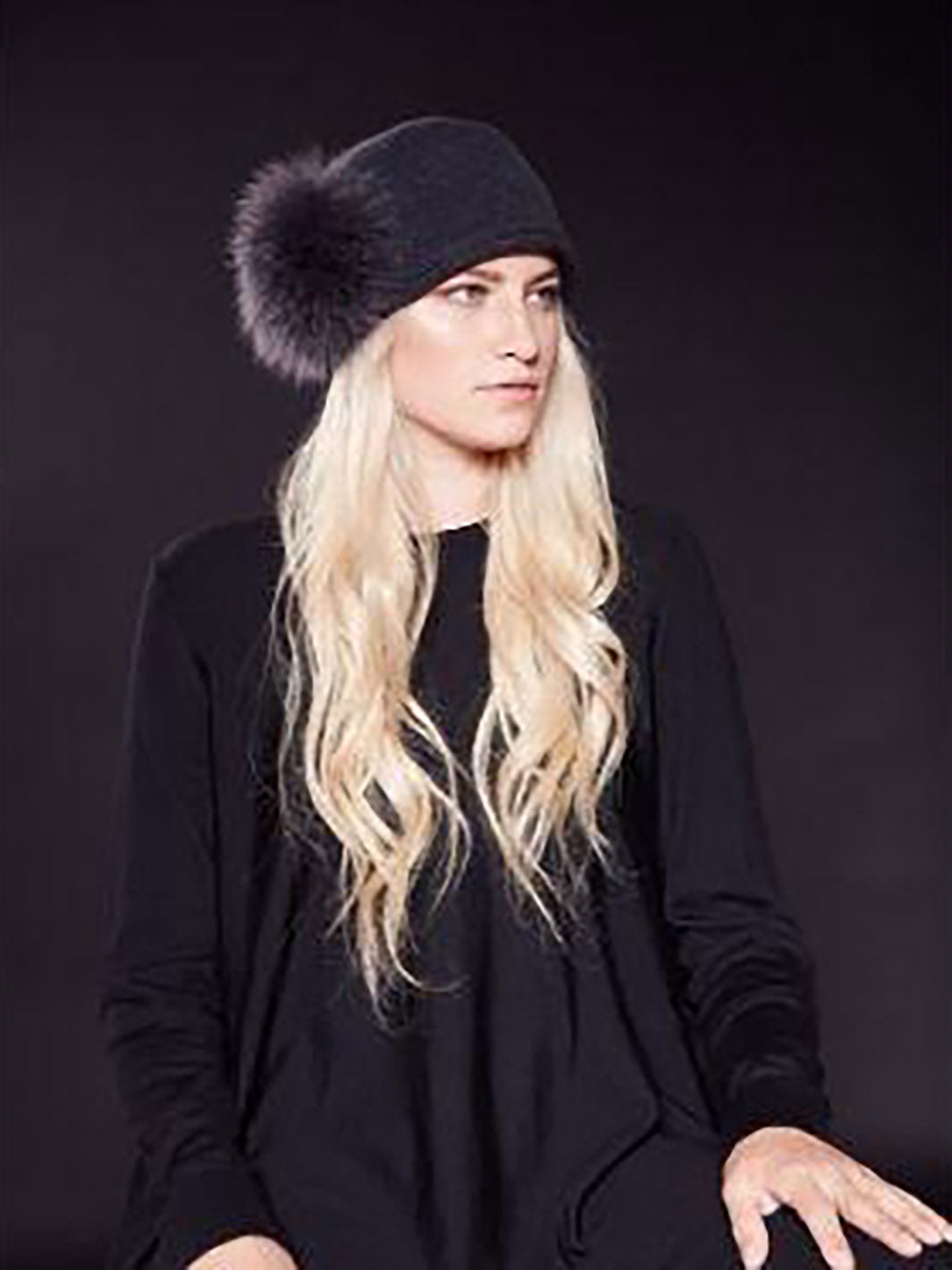 Mannequin femme portant un chapeau noir en laine avec pompom en fourrure recyclée sur le coté