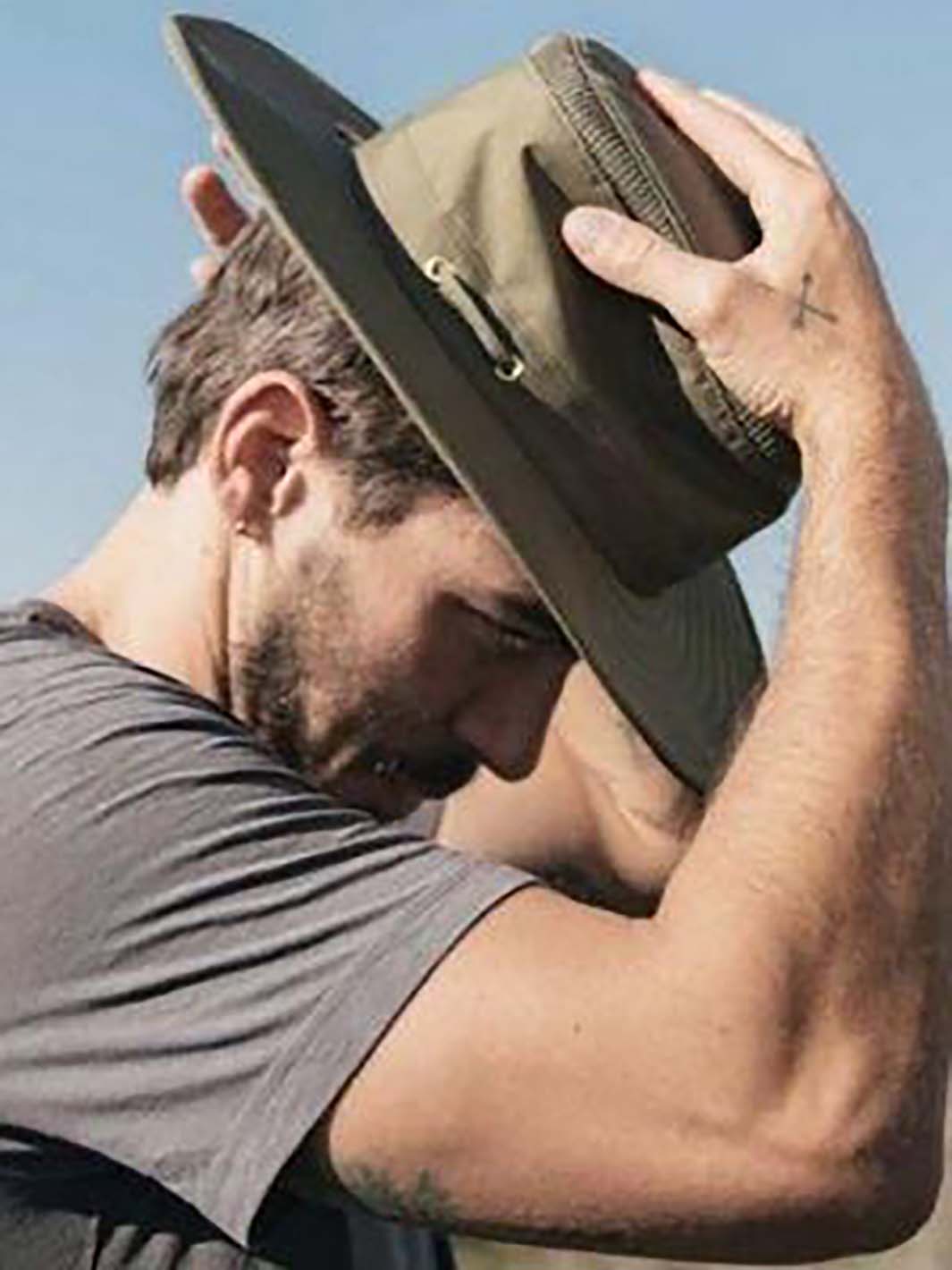 Homme mettant un chapeau de plein air à l'extérieur