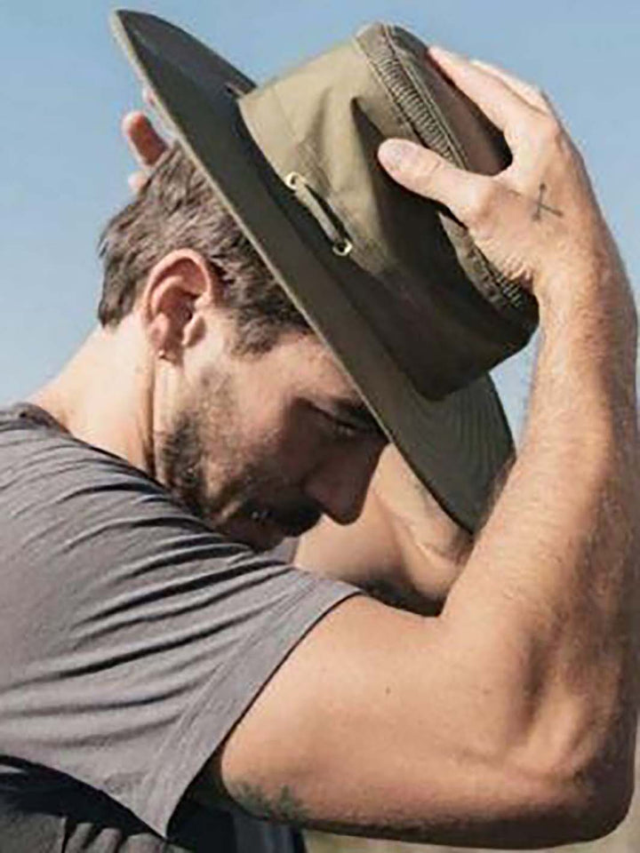 Homme mettant un chapeau de plein air à l'extérieur