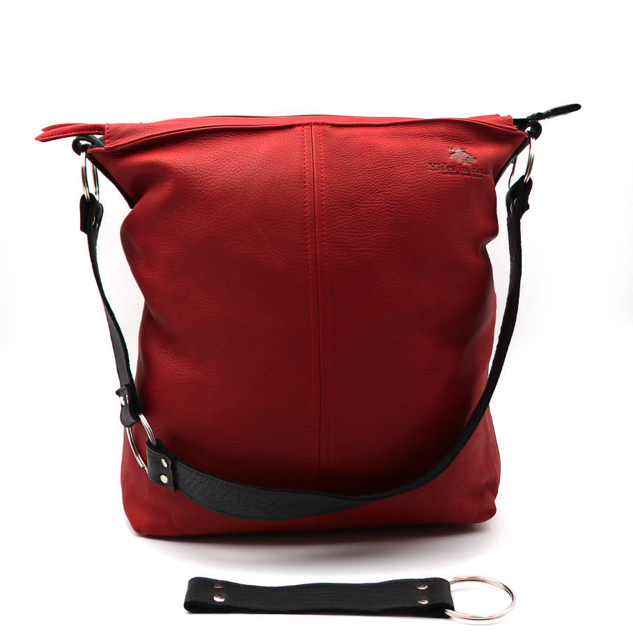 Sac à main fourre-tout rouge avec le logo de la compagnie à droite et la sangle tombante et la rallonge devant le sac