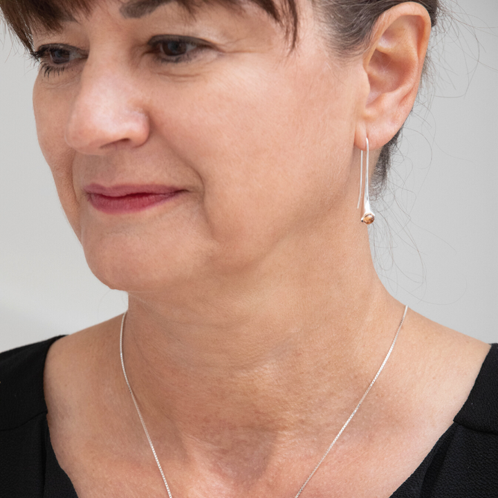 Femme portant une longue boucle d'oreille et une chaine autour du cou