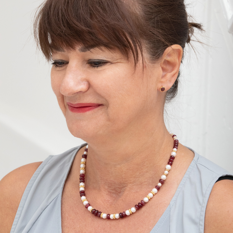Femme portant une boucle d'oreille rouge et un collier de pierres rouges et blanches