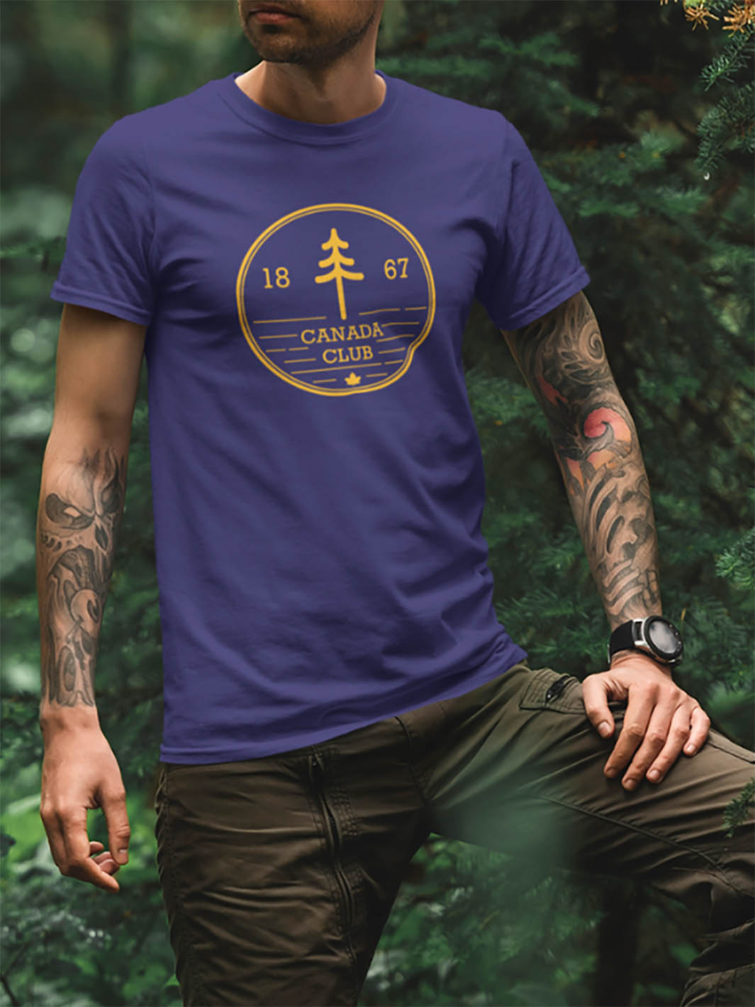 Mannequin dans la foret portant un tshirt bleu avec un motif d'un cercle avec un arbre, l'année 1867 et CANADA CLUB inscrit