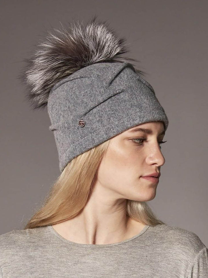 Mannequin femme de profil portant une tuque grise en laine avec pompom en fourrure recyclée