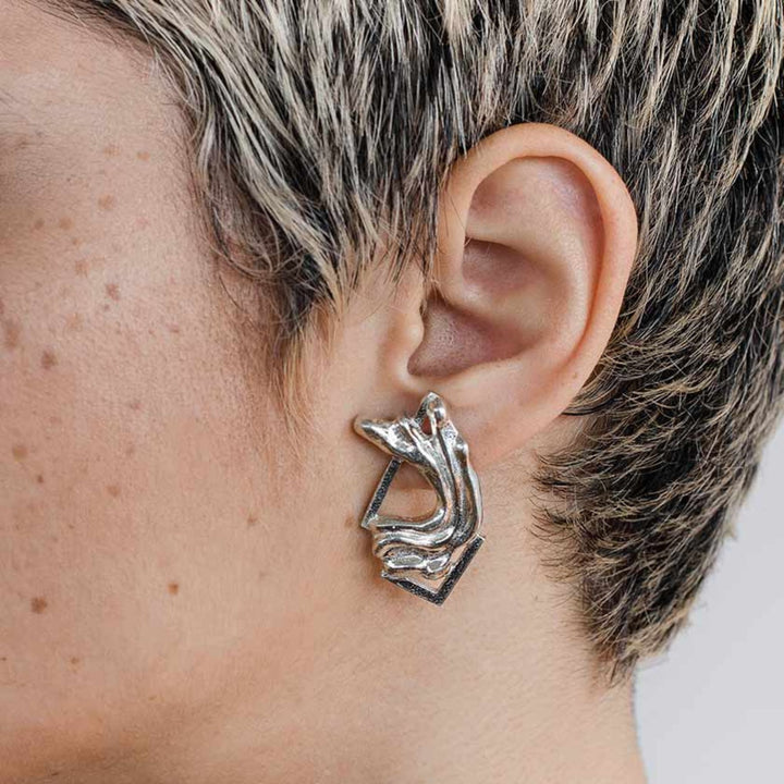 Femme portant des Boucles d'oreilles Anne-Marie Chagnon Pada en forme abstraite en étain