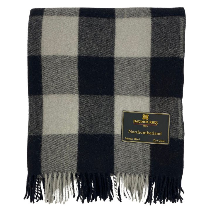 Lourde couverture tartan Northumberland noire et grise pliée avec franche dans le bas et étiquette Patrick king dans le bas droit