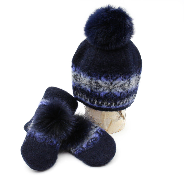 Tuque et mitaines en laine islandaise marine et bleue pâle avec pompom bleu marine déposées sur une buche