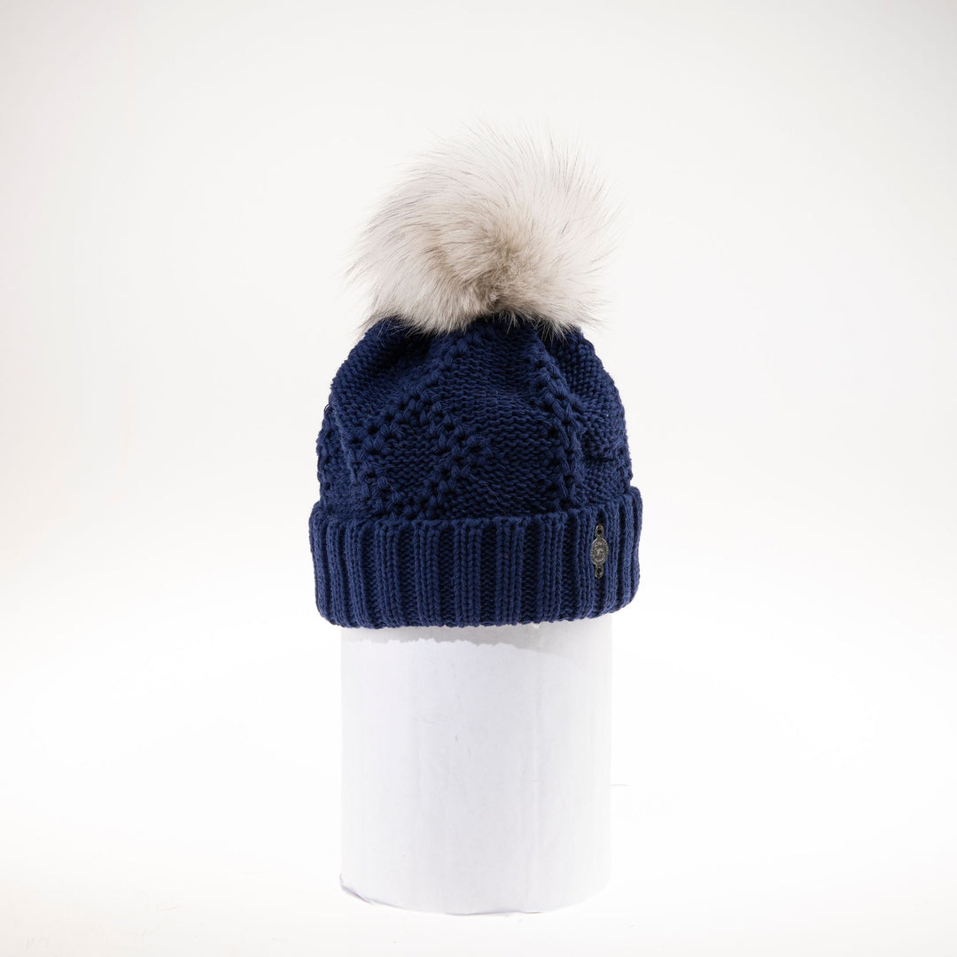 tuque en grosses mailles de couleur marine avec un pompom de fourrure beige sur le dessus