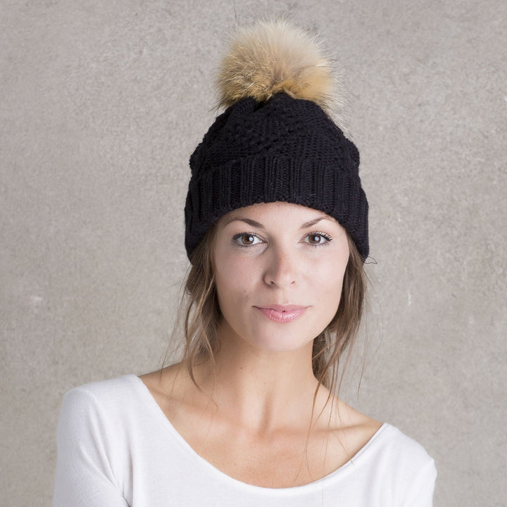 mannequin femme qui porte la tuque noir avec un pompom beige de fourrure