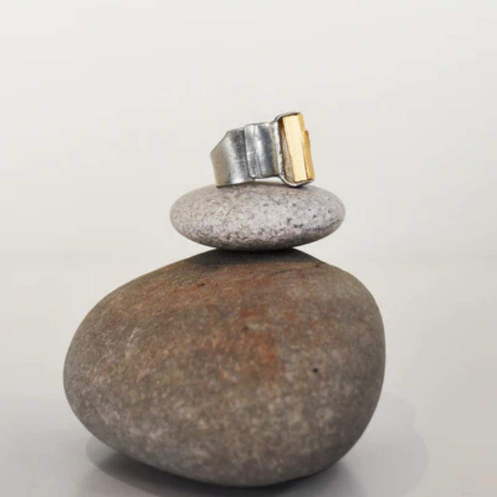 Bague Ogma argentée et dorée déposée sur des pierres par Anne-Marie Chagnon