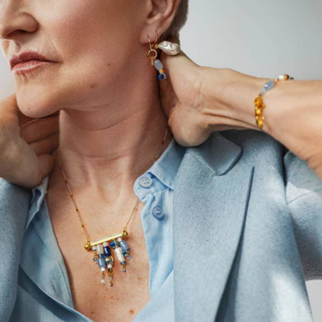 Femme portant des bijoux Anne-Marie Chagnon dorés et bleus de la collection printemps-été 2026