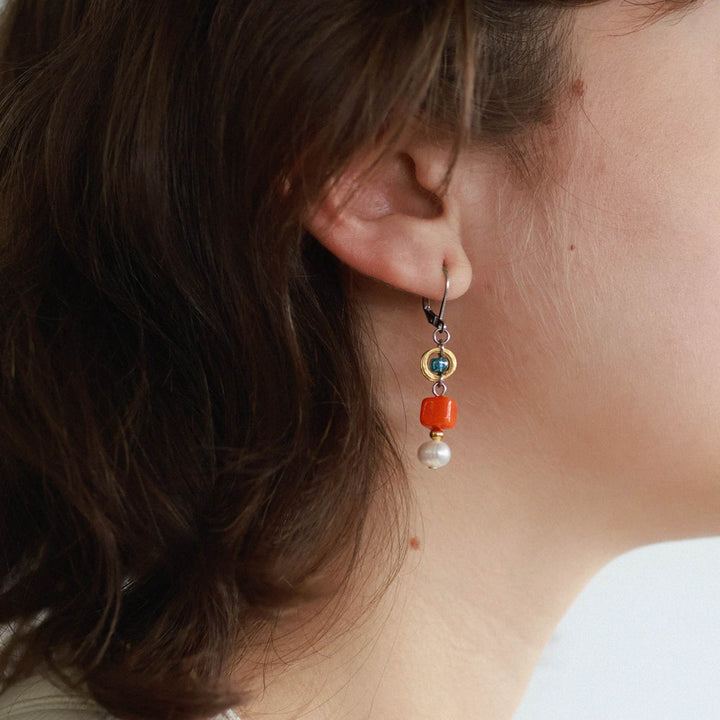 Femme portant une Boucle d'oreilles avec pierres oranges et turquoises suspendues par Anne-marie Chagnon