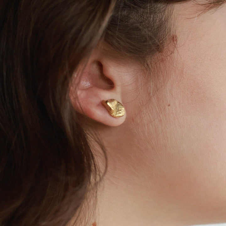 Oreille de femme avec une Boucle d'oreilles clou avec une pièce en étain plaqué or par Anne-Marie Chagnon