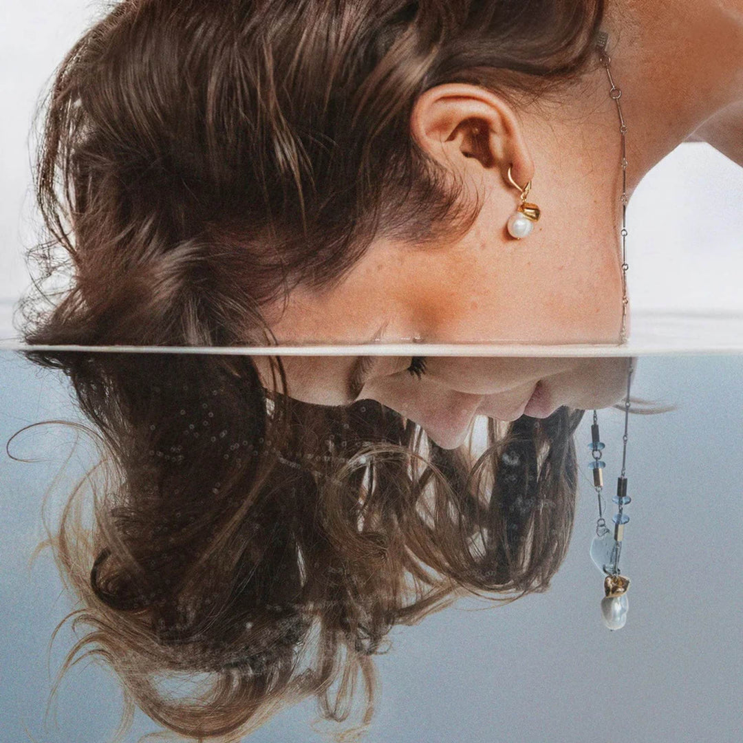 Femme plongeant sa tête dans l'eau portant des Boucles d'oreilles dorées par Anne-Marie Chagnon
