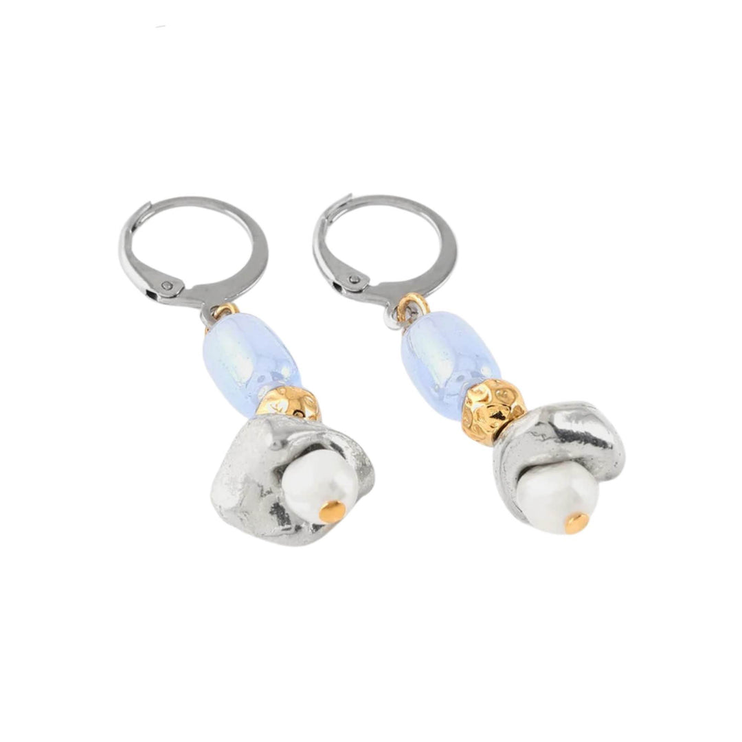 Boucles d'oreilles pendantes argentées et dorées avec perle bleue au centre par Anne-Marie Chagnon vues de près