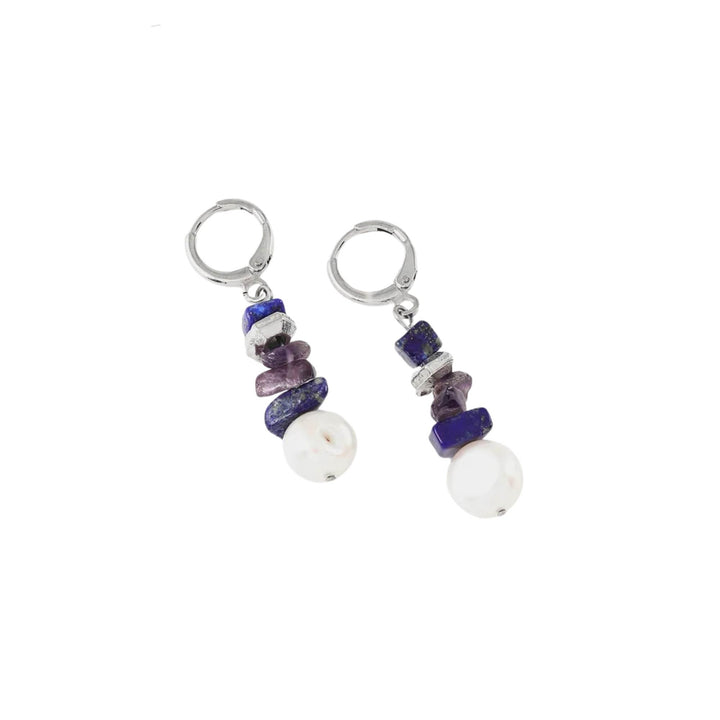 Boucles d'oreilles bleues et mauves avec perle suspendue par ANne-Marie Chagnon déposées sur une surface