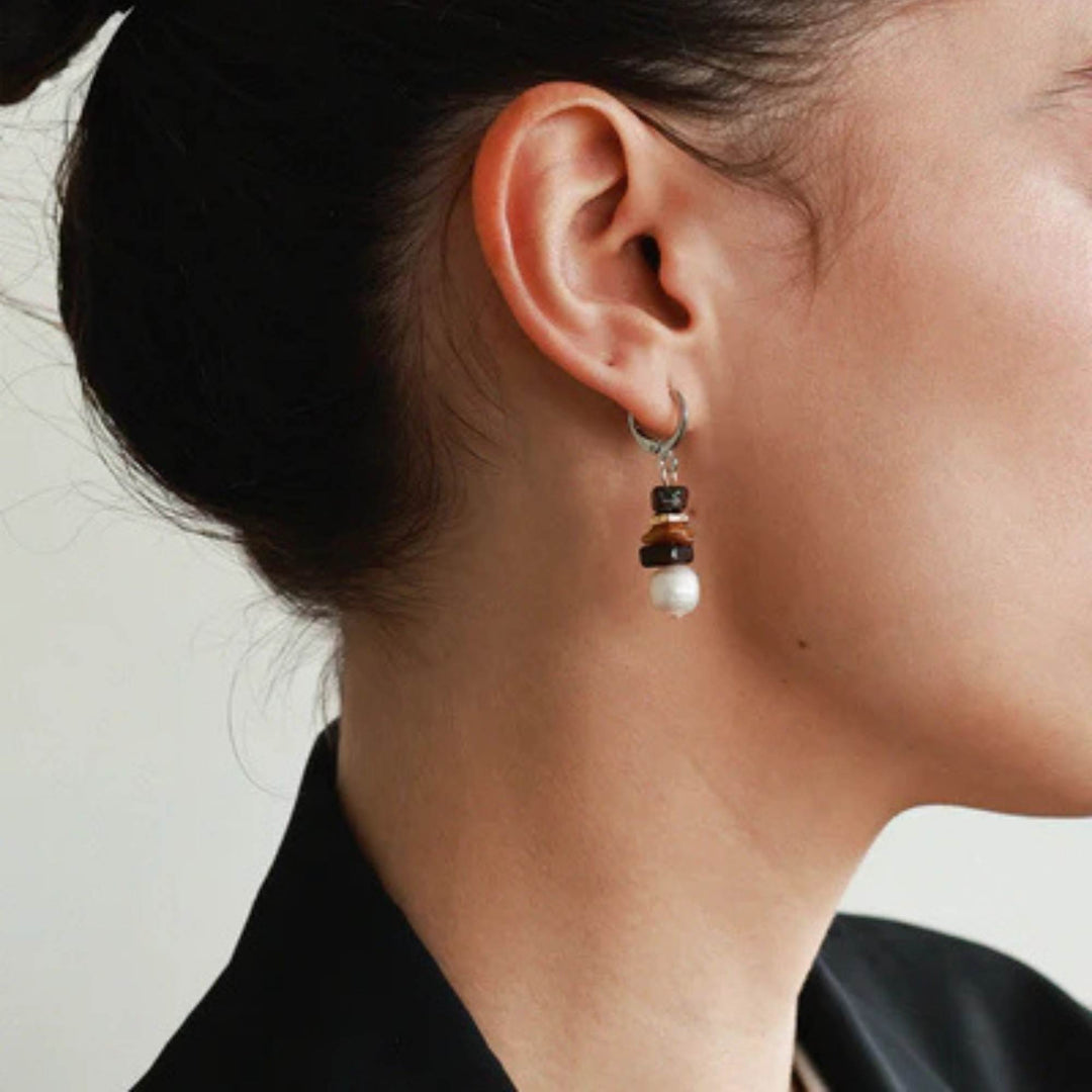 Femme portant des Boucles d'oreilles brunes suspendues par Anne-Marie Chagnon