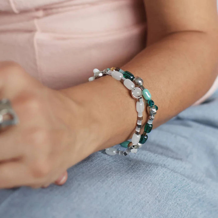 Femme portant des bracelets avec billes de verre turquoises et pièces en étain brut par Anne-Marie Chagnon