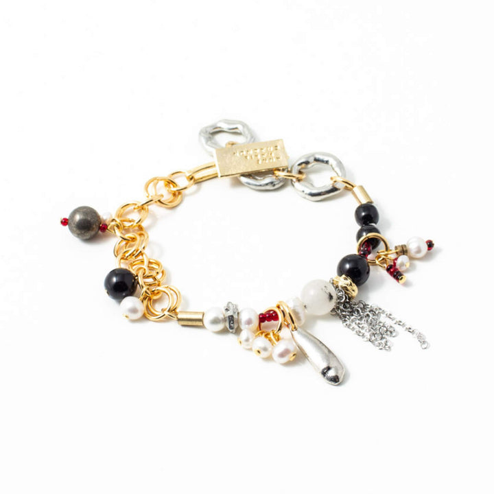 Bracelet Anne-Marie Chagnon Olean doré avec perles blanches et noires, billes rouges et breloques en étain