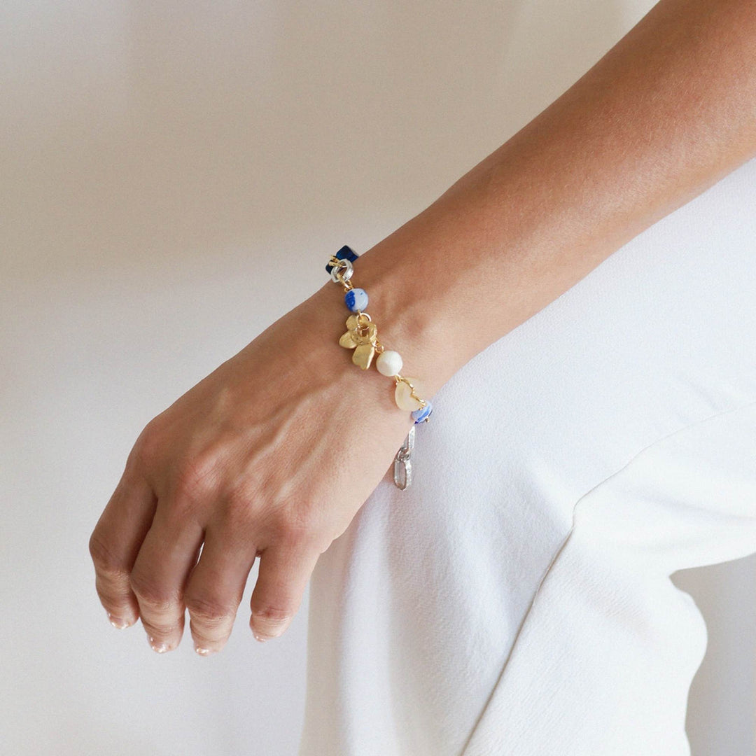 Poignet avec un Bracelet Elnath argenté et or avec pierres bleues par Anne-Marie Chagnon