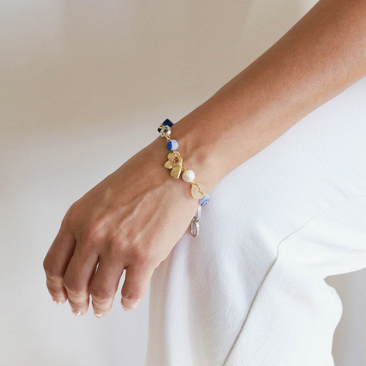 Poignet avec un Bracelet Elnath argenté et or avec pierres bleues par Anne-Marie Chagnon