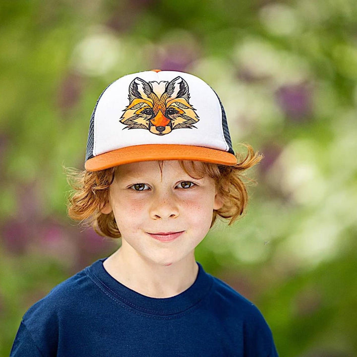 Enfant dans la forêt portant une Casquette blanche, orange et noire avec un motif de renard sur le devant