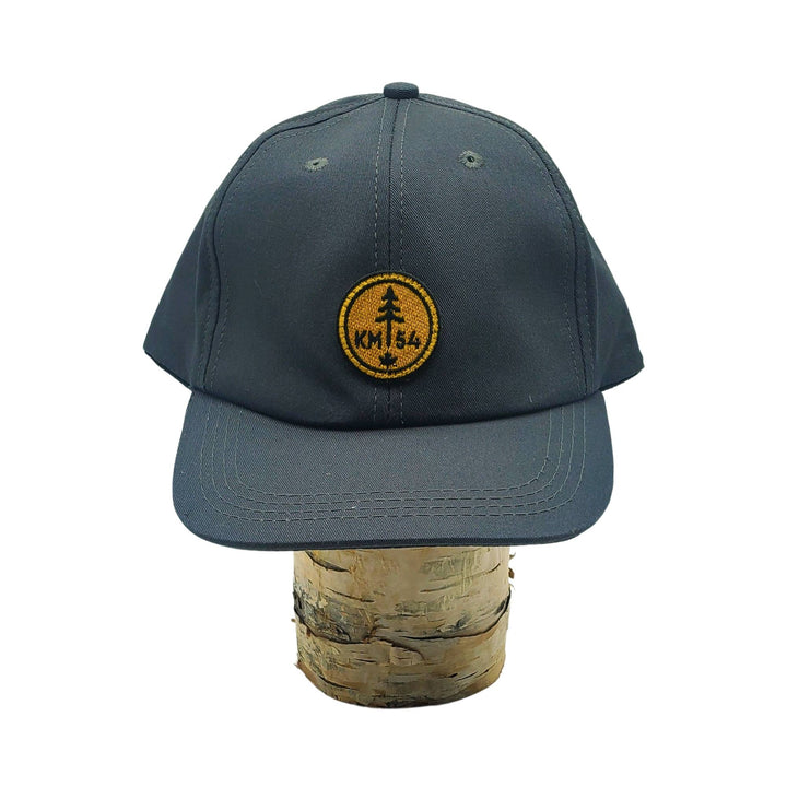 Casquette grise KM54 sur une bûche avec le logo brodé sur le devant