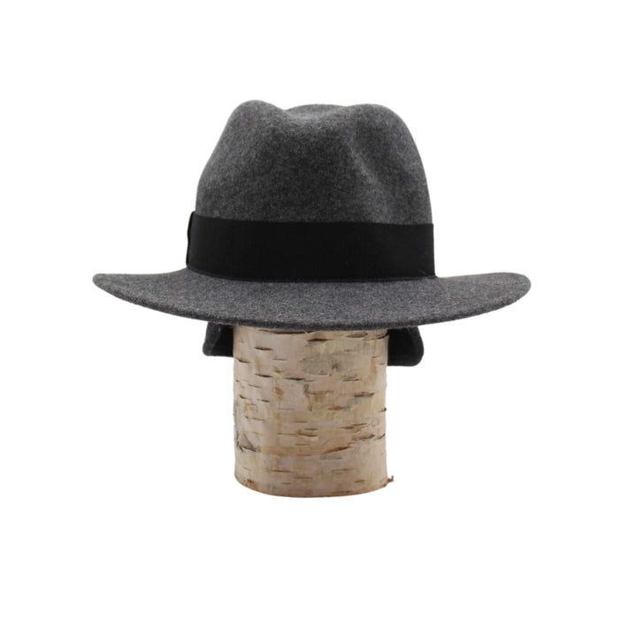 Chapeau fedora Fearn en laine gris avec un ruban noir déposé sur une bûche vu de devant avec les rabats d'oreilles