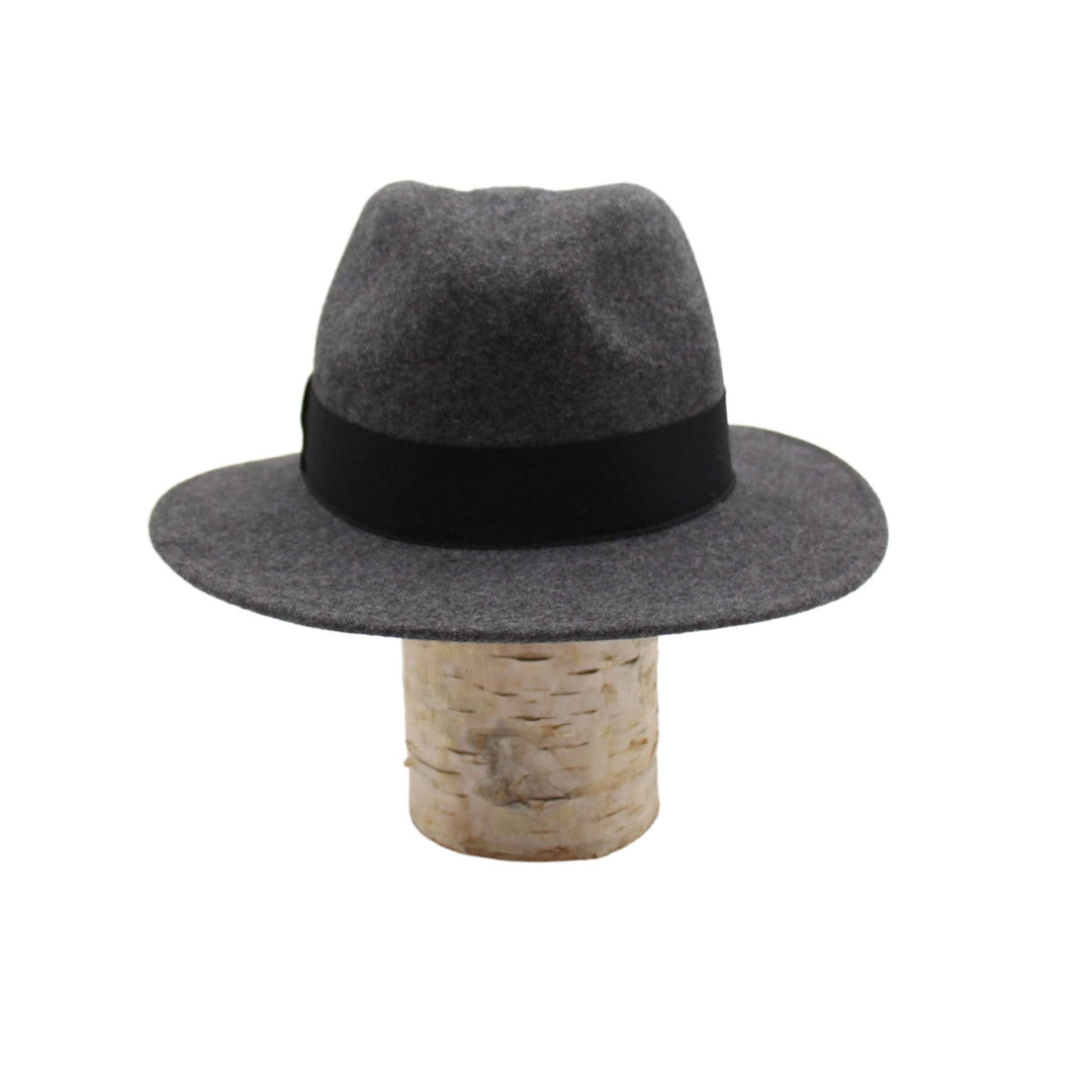 Chapeau fedora Fearn en laine gris avec un ruban noir déposé sur une bûche
