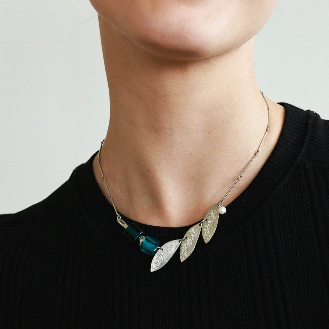 Femme portant un Collier Gienah avec pierres bleues et feuilles en étain par Anne-Marie Chagnon