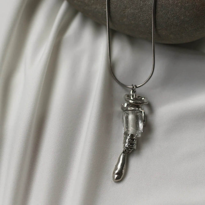 Collier Gliese avec pendentif en verre suspendu par Anne-Marie Chagnon déposé sur un tissus