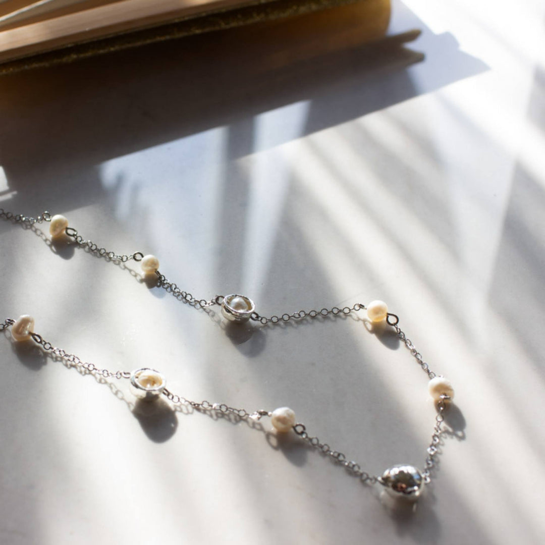 Collier Isadora argenté avec perles et chaîne par Anne-Marie Chagnon vu de dessus dans la lumière