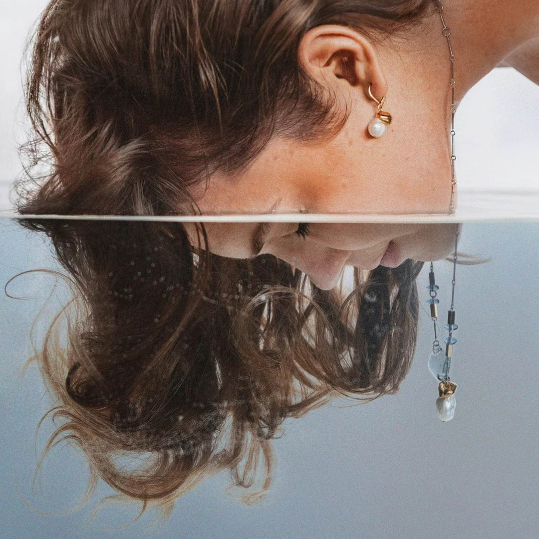 Femme plongeant sa tête dans l'eau portant un Collier avec verre bleu Isaria par Anne-Marie Chagnon