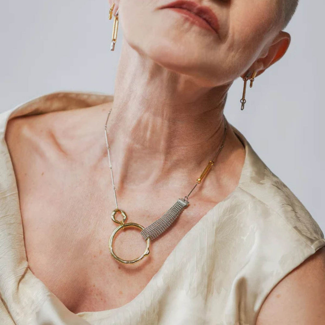Femme tournée vers l'appareil photo portant un Collier en étain et plaqué or  Kauri par Anne-Marie Chagnon