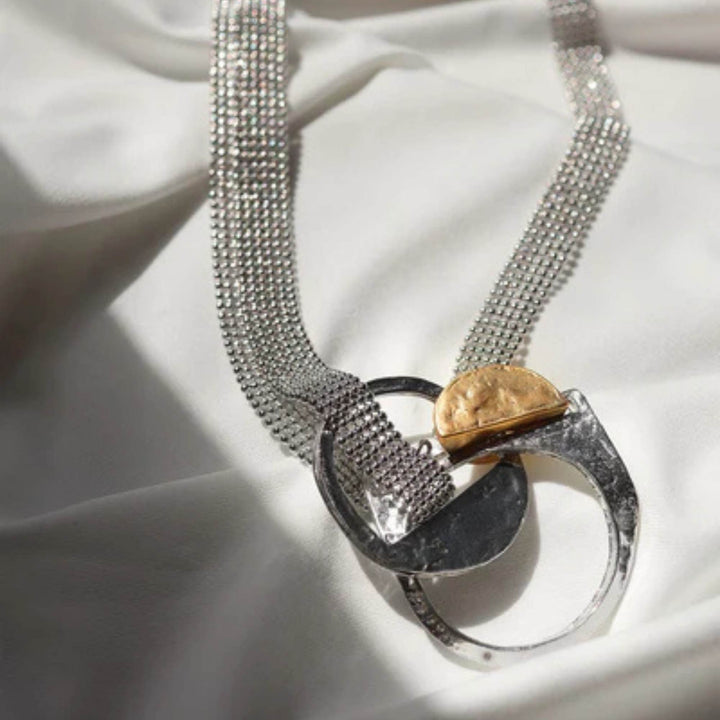 Collier Mercury en étain et plaqué or par Anne-Marie Chagnon désposé sur un tissus