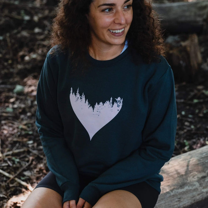 Femme assise dehors portant un coton ouaté charcoal avec un coeur et une forêt rose par KM54